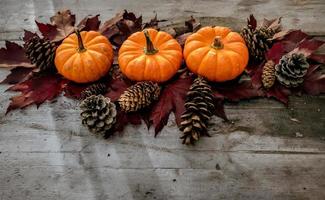 feestelijk herfstdecor van pompoenen, dennen en bladeren op een houten ondergrond. concept van thanksgiving day of halloween. plat lag herfstcompositie met kopieerruimte. foto