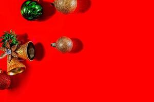 kerst achtergrond concept. bovenaanzicht van kerst gouden klokken met ballen decoratie, vuren takken, ster en sneeuwvlokken op rode achtergrond. foto