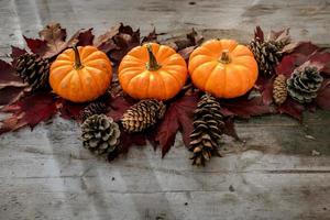 feestelijk herfstdecor van pompoenen, dennen en bladeren op een houten ondergrond. concept van thanksgiving day of halloween. plat lag herfstcompositie met kopieerruimte. foto