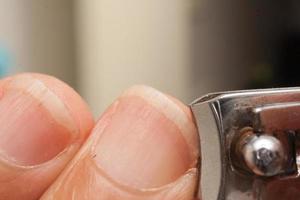 man knipt zijn vingernagels met een paar nageltrimmers foto