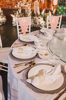 bloemstuk voor zomerhuwelijk, gemaakt van rozen en groene takken op een eettafel in het restaurant. , glas en borden in het restaurant buiten op een winderige dag met filmkorreleffect foto