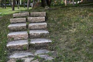 een stenen pad in het park en een granieten trap met treden. stenen trap in de tuin. foto