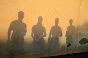 schaduw van vier vrienden tegen een muur tijdens zonsondergang foto