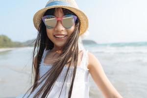 portret klein Aziatisch meisje op zee strand kijken camera gelukkig vakantie concept foto