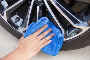 hand met blauwe microvezeldoek die autowiel schoonmaakt. foto