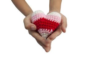 de hand van het kind met haak varicolored hartvorm gemaakt van garen voor uw dierbaren op Valentijnsdag geïsoleerd op een witte achtergrond opgenomen uitknippad. foto