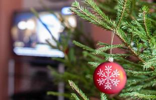 glazen bol op takjes kerstboom en tv-toestel foto