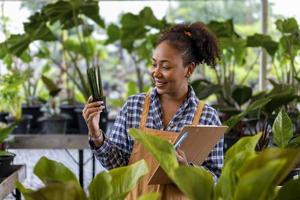 Afro-Amerikaanse tuinman werkt in haar kas in het kwekerij-tuincentrum voor het concept van inheemse en exotische plantenkwekers foto