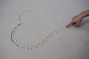 harten getekend op het zand van een strand foto