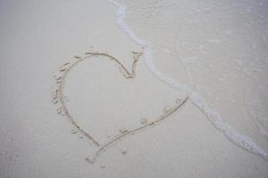 harten getekend op het zand van een strand foto