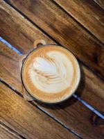 mooie kop cappuccinokoffie met latte art op de houten ruimteachtergrond foto