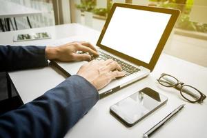 zakenmanhanden die met digitale tabletcomputer en slimme telefoon met bedrijfsgrafiek op bureau als concept werken. foto