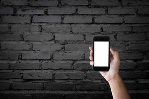man met leeg scherm van een smartphone op de oude zwarte bakstenen muur. foto