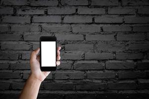 man met leeg scherm van een smartphone op de oude zwarte bakstenen muur. foto