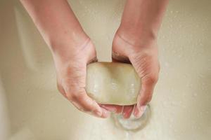 bovenaanzicht van jonge man handen wassen met zeep warm water foto