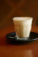 een kopje late koffie met bloemvormig ontwerp bovenop in café foto