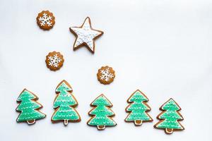 handgemaakte feestelijke peperkoekkoekjes in de vorm van sterren, sneeuwvlokken, mensen, sokken, personeel, wanten, kerstbomen, harten voor kerstmis en nieuwjaarsvakantie op witboekachtergrond foto