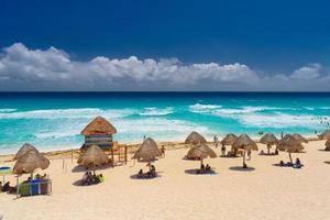 paraplu's op een zandstrand met azuurblauw water op een zonnige dag in de buurt van cancun, mexico foto