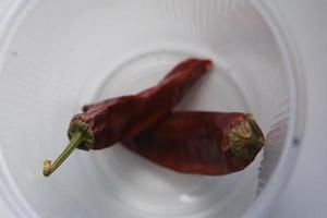 rode rijpe biologische tomaten en gedroogde hete rode peper op de vensterbank foto