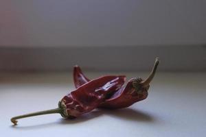 rode rijpe biologische tomaten en gedroogde hete rode peper op de vensterbank foto