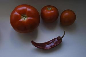 rode rijpe biologische tomaten en gedroogde hete rode peper op de vensterbank foto