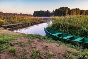 oude houten boot in de rietstruiken aan de oever van een brede rivier of meer foto