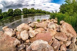 enorme stenen aan de oevers van een brede rivier op een bewolkte dag foto