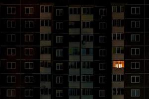 licht in één raam. plat nachtpanorama van veelkleurig licht in ramen van gebouwen met meerdere verdiepingen. leven in de grote stad foto