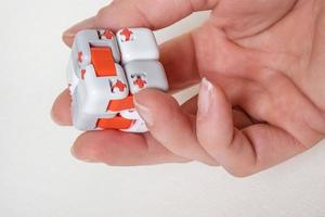 kleurrijke vingers antistress fidget kubus speelgoed in de hand op witte achtergrond. ontwikkeling van fijne motoriek van vingers van kinderen foto