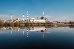 pijpen van houtbewerking onderneming plant zagerij in de buurt van rivier. luchtvervuiling concept. industrieel landschap milieuvervuiling afval van thermische elektriciteitscentrale foto