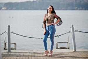mooie latino model meisje uit ecuador slijtage op jeans gesteld tegen meer. foto