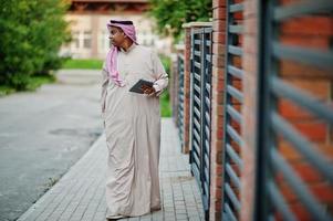 Arabische man uit het Midden-Oosten poseerde op straat tegen modern gebouw met tablet bij de hand. foto