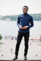 Afrikaanse man poseerde in de straat van de stad, droeg een blauw shirt en een zwarte broek. foto