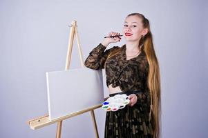 mooie vrouw kunstenaar schilder met borstels en olie canvas poseren in studio geïsoleerd op wit. foto