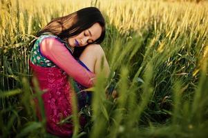 teder indisch meisje in saree, met paarse lippen make-up geposeerd op het veld bij zonsondergang. modieus Indiaas model. foto