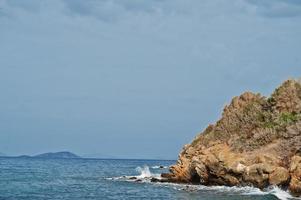 zee golf breekt op strand rotsen landschap. zeegolven crashen en spatten op rotsen in bodrum, turkije. foto