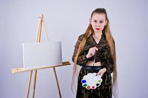 mooie vrouw kunstenaar schilder met borstels en olie canvas poseren in studio geïsoleerd op wit. foto