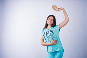 portret van een aantrekkelijk meisje in blauw of turquoise t-shirt en broek poseren met veel geld in haar hand. foto