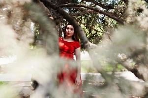 tienermeisje in rode jurk poseerde buiten op zonnige dag. foto