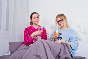 twee vrienden meisjes in pyjama plezier op bed op kamer. foto