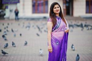 indiase hindoe meisje op traditionele violet saree poseerde op straat tegen duiven. foto