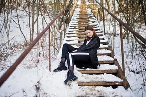 modieuze lange benen brunette model in lange zwarte mantel poseerde buiten op winterdag. foto