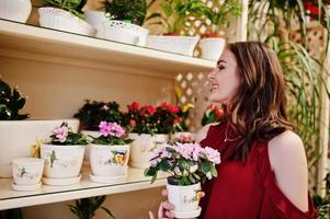 brunette meisje in het rood bloemen kopen bij bloemenwinkel. foto