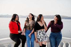 groep van vier gelukkige en mooie latino-meisjes uit ecuador poseerden tegen de kant van het meer. foto