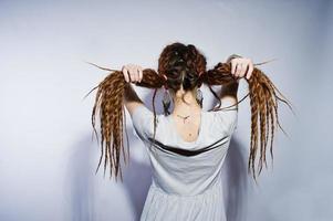 studio shoot achterkant meisje in grijze jurk met vlechten dreadlocks op witte achtergrond. foto