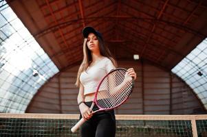 jonge sportieve meisjesspeler met tennisracket op tennisbaan. foto