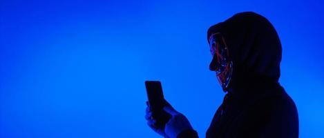 anonieme hacker en gezichtsmasker met smartphone in de hand. foto