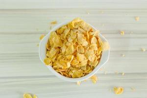 afbeelding close-up cornflakes granen ontbijt in witte kom op houten tafel. foto