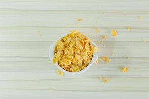 afbeelding close-up cornflakes granen ontbijt in witte kom op houten tafel. foto