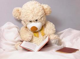 schattige beige teddybeer voor kinderen die met een bril spelen leest een boek foto